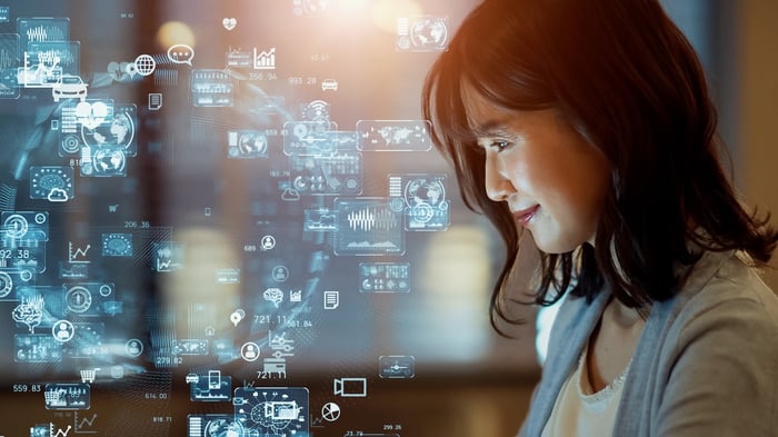 A person smiles while looking at a swirl of digital icons.