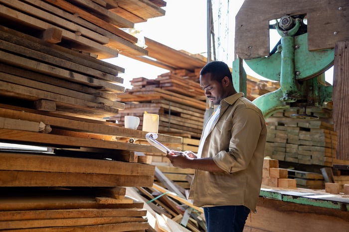 Someone looking at a big pile of wood.