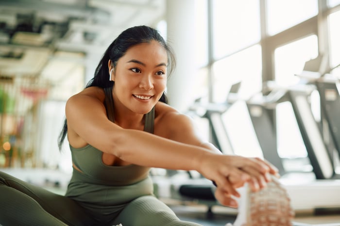 Person in a gym, stretching and smiling.