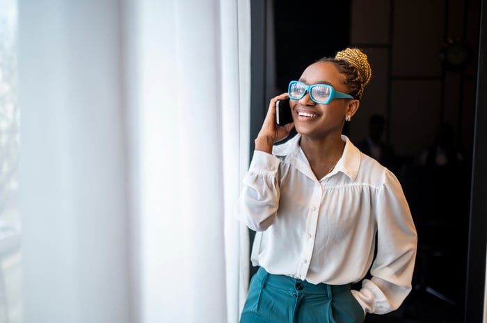 Person talking on the phone wearing glasses with a brightly colored frame.