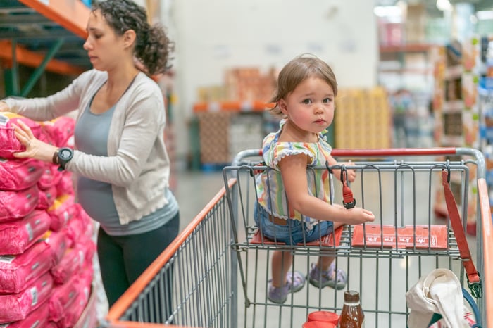 A parent and child in a wagon at a warehouse store.