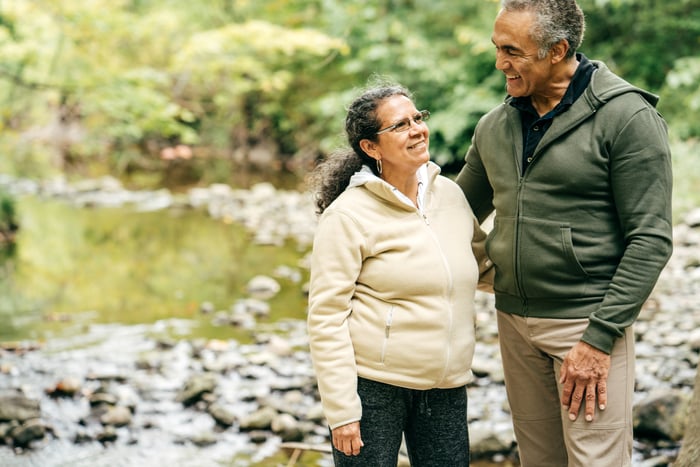 Smiling couple standing by a river.