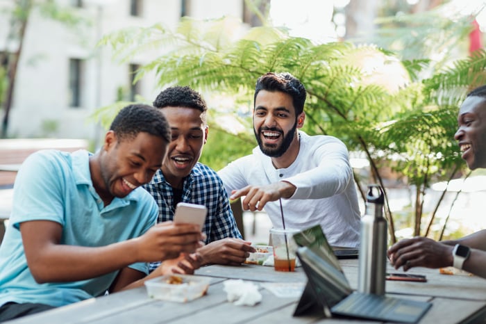 People laughing at a meme on someone's phone.