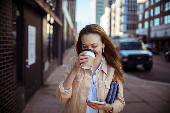 Person drinking coffee and walking outside.