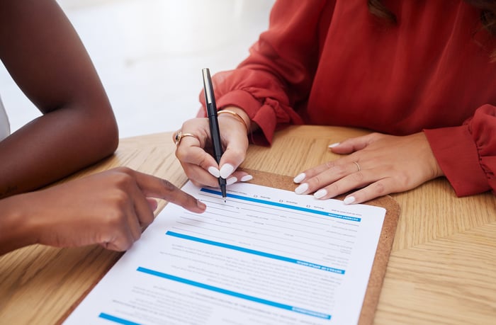 Two people signing a form.