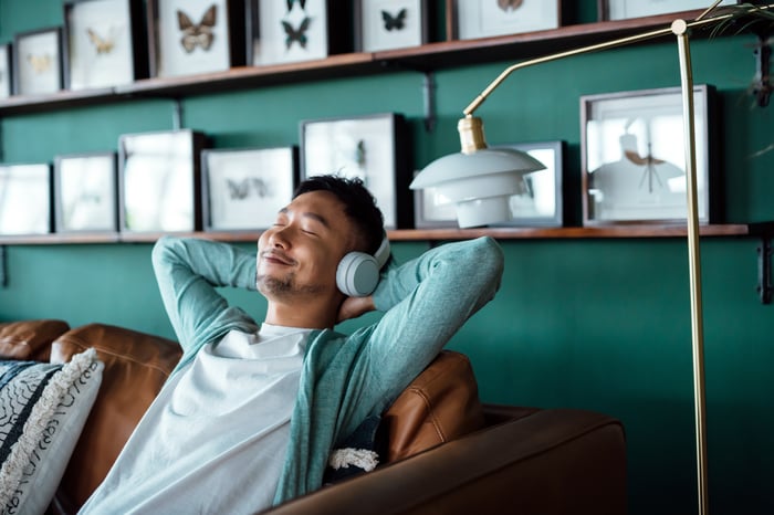 A smiling person wears mint-green headphones.