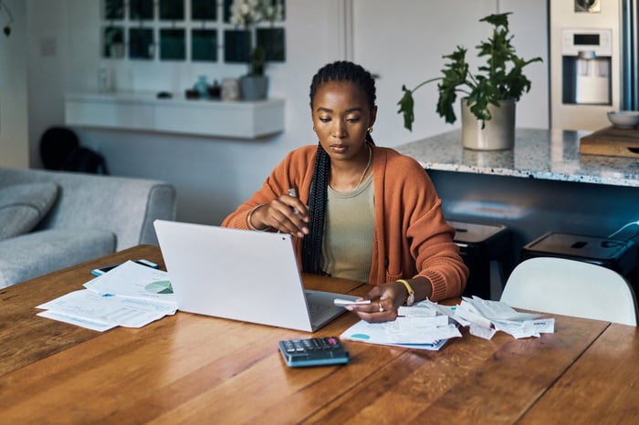 Professional working with laptop and calculator in a home environment.