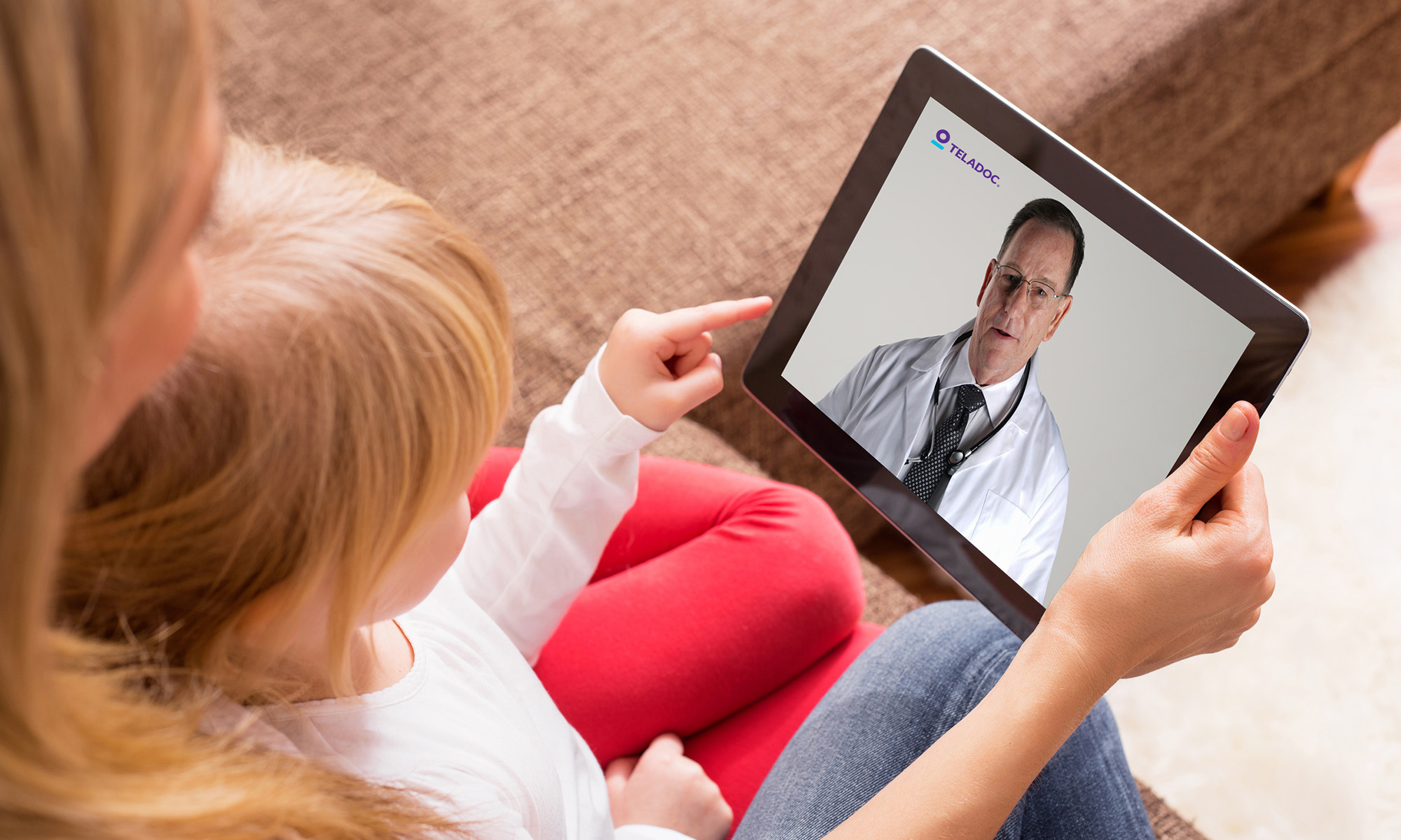 person using tablet for doctor visit for child with teladoc health logo on screen_teladoc
