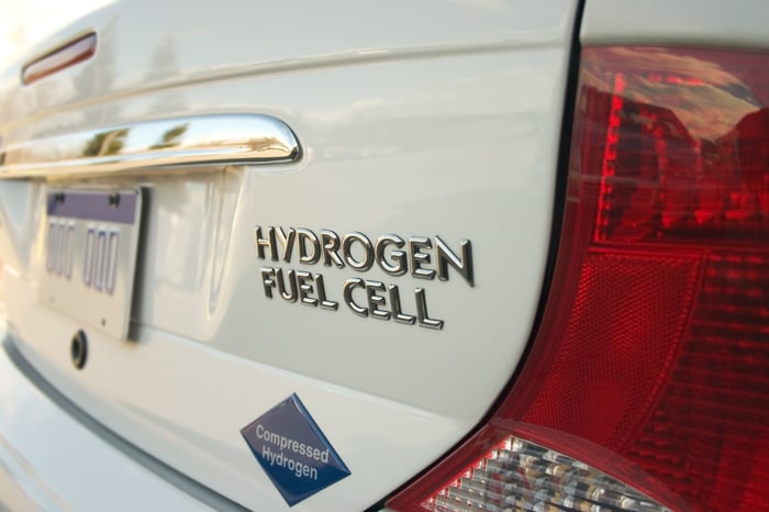 A hydrogen fuel cell emblem and badges on the trunk of a white sedan.