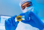 person in a mask looking at a semiconductor microchip for artificial intelligence (AI)