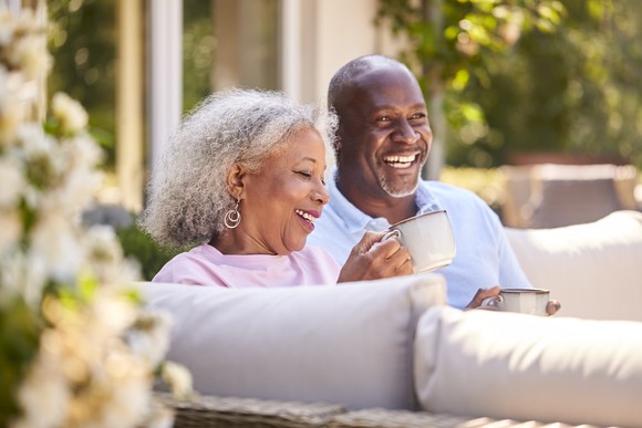 Smiling couple enjoying coffee on patio.