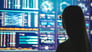 A businessperson standing near a display with various charts and graphs