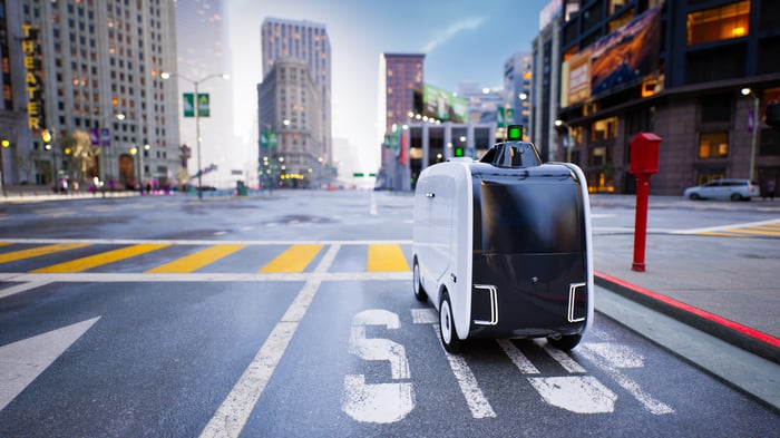 Food delivery robot on a city street next to a painted stop sign.