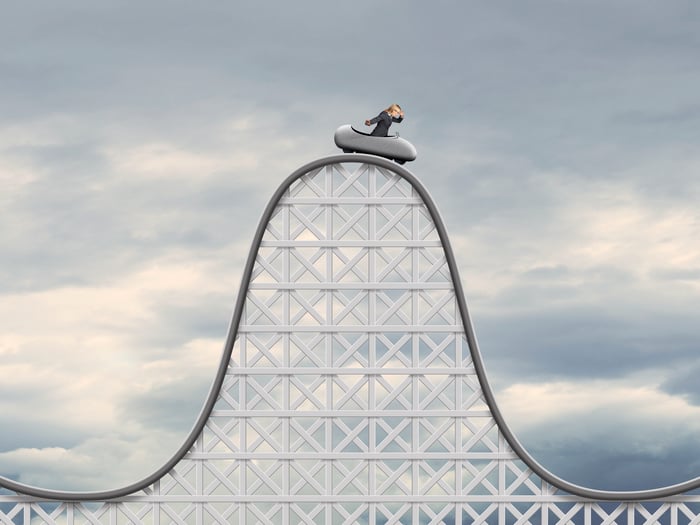 A person at the peak of a roller coaster, preparing for a rapid descent.