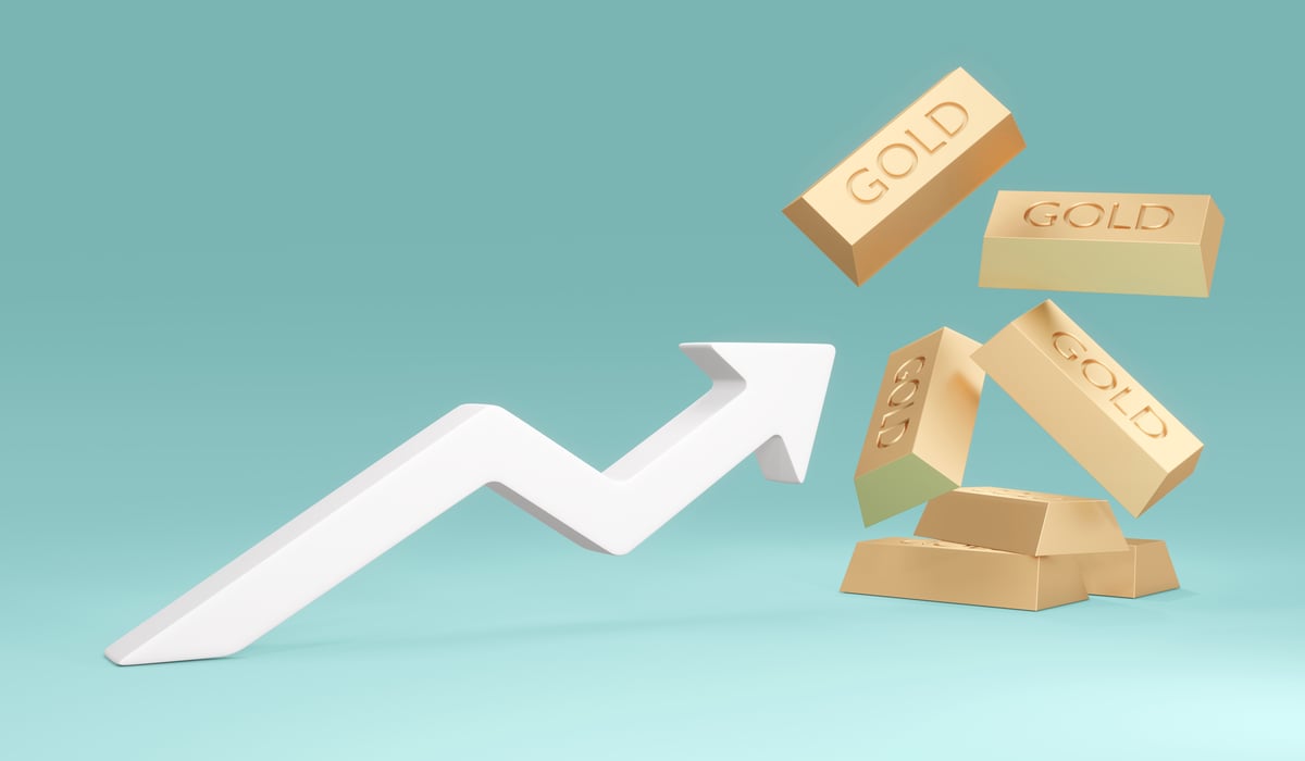 An upward-sloping arrow hitting wooden blocks that say “gold,” showcasing gold hitting record highs.