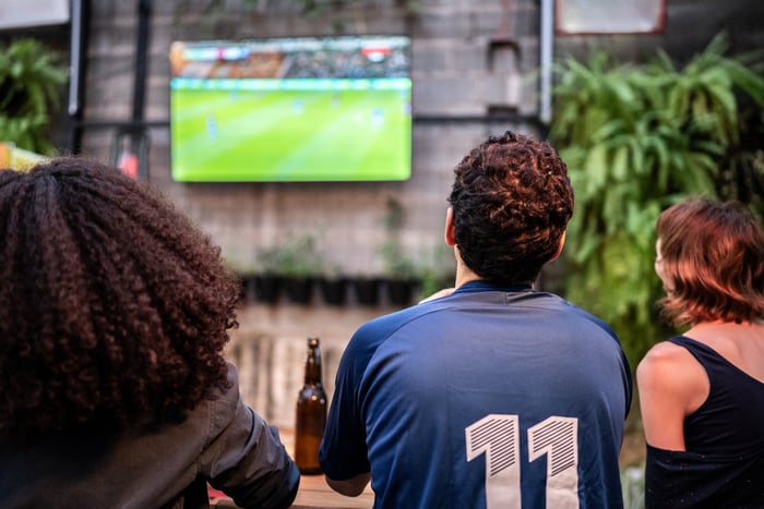 Group of people watching a sports event on TV.