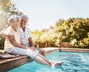 Smiling seniors sitting by a pool