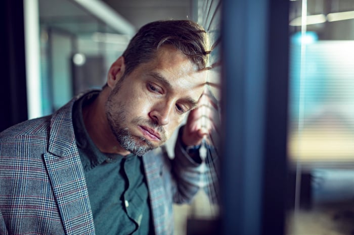 A person leaning against a window about to let out a large sigh. 
