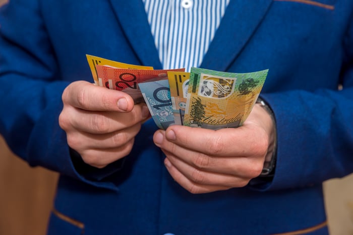 A person holding in their hands an assortment of bills of different values.