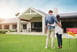 A couple standing in front of their new home, with a sold sign out the front
