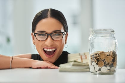 A person with a big smile looking at their jar of financial savings