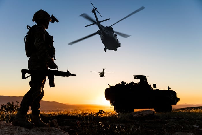 Military operations with a tank and helicopters underway at sunrise.