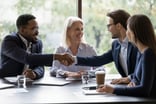 Two_businessmen_shaking_hands_in_a_team_meeting