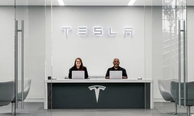 tesla service center with two associates at desk with tesla logo