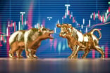 A gold bull and bear facing off in front of a large stock market chart