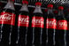 row of coca-cola bottles lined up in fridge
