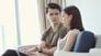 Couple talking while woman looks at laptop