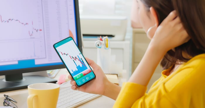 A person looking at a phone displaying a stock chart.