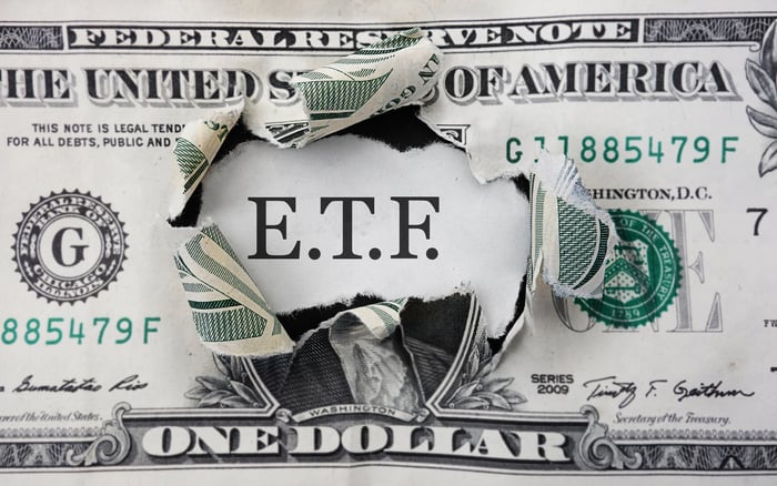 E.T.F. showing through the middle of a ripped dollar bill.