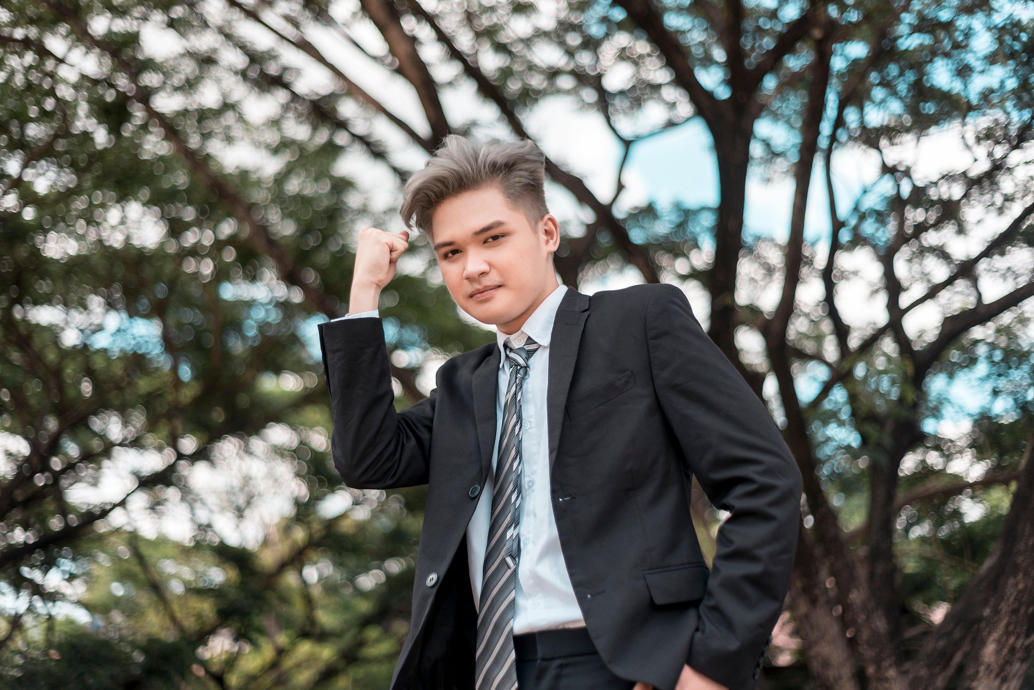 A confident and brash young man in business attire pumps his fist up in victory