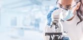 Person in a lab gazing into a microscope