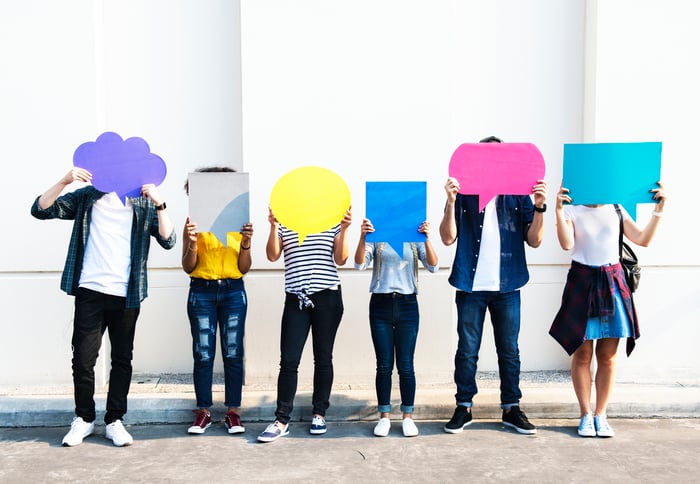 Six young people hold cardboard cutouts of speech and thought bubbles.