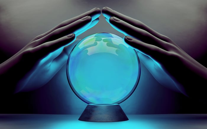Two hands over a blue, glowing crystal ball.