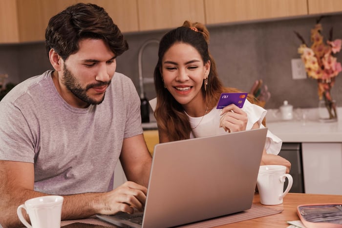 Two people with a computer and a Nu credit card.