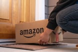 Amazon box with logo being dropped on a porch