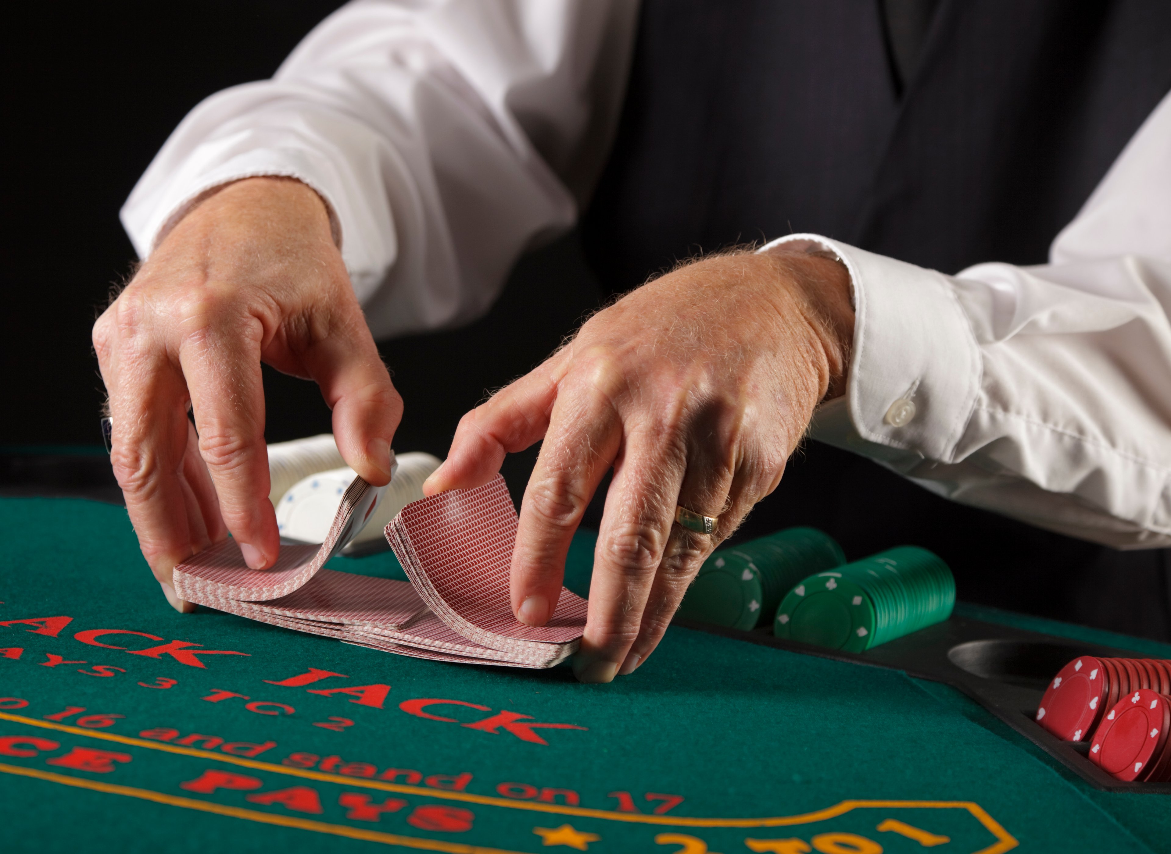 Hands of a dealer shuffling cards at a gambling table