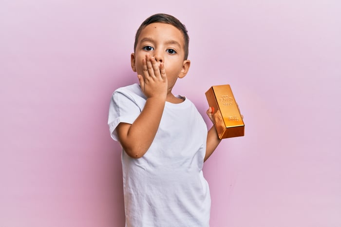 A toddler holds a gold bar.