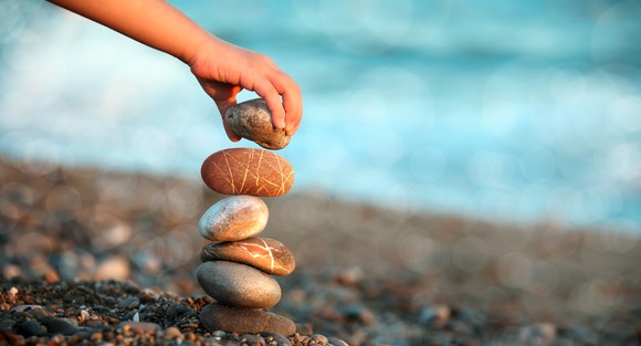 A person stacks stones on a shoreline.