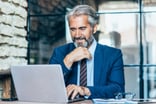 Man older business suit laptop GettyImages-1193688718
