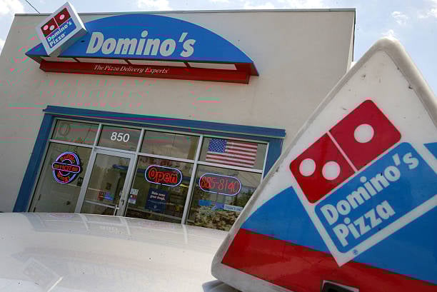 The outside of a Domino's Pizza location with its red and blue logo featured.