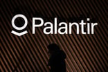 Palantir logo on the wall above the shadow of a person walking by