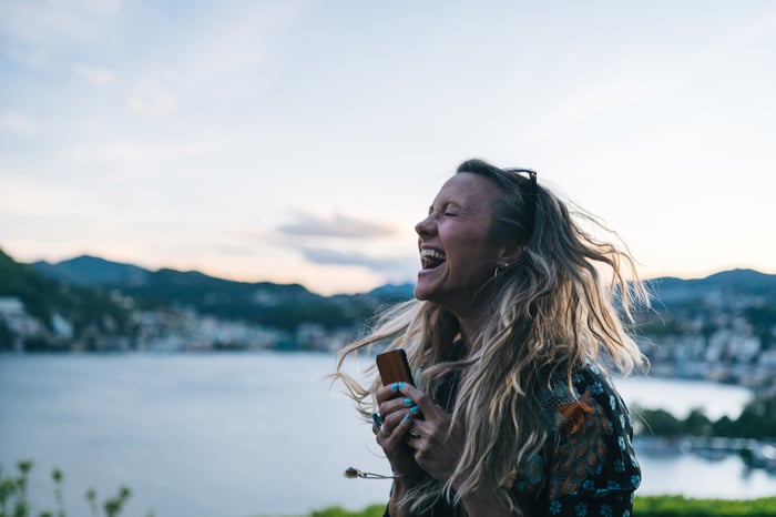 An investor jumps with excitement while holding a phone outdoors.