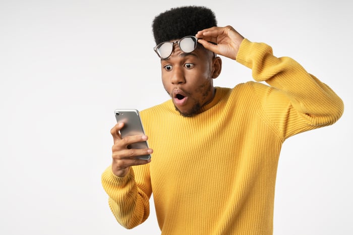 Young investor looking shocked at something on their phone.