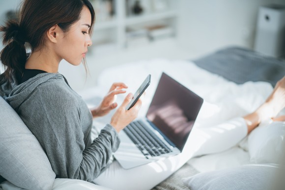 A person shopping online on a phone and computer.