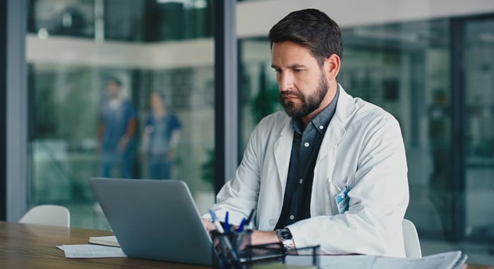 Healthcare professional reviewing reports on a computer.