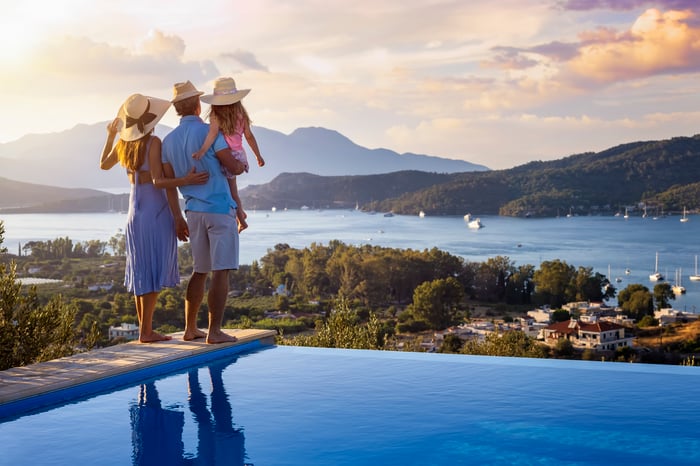 A family standing beside a pool, looking out at a lake.
